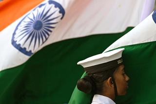 A naval officer in front of the Indian flag.